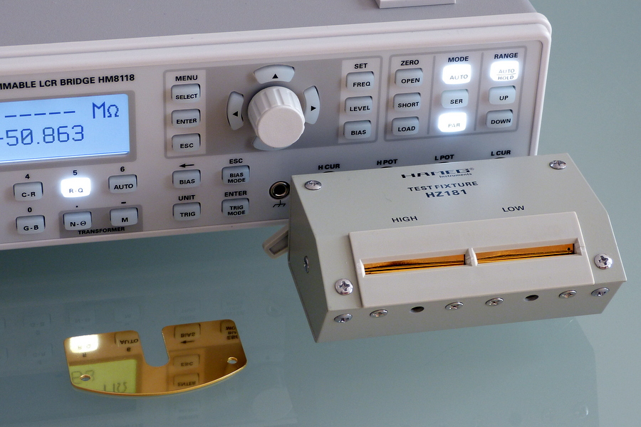 Figure 1 — A benchtop LCR meter with its four-terminal test fixture. It applies a small AC signal at a selectable frequency and resolves the complex impedance into C, ESR/DF, and Q. Source: CookMeS…