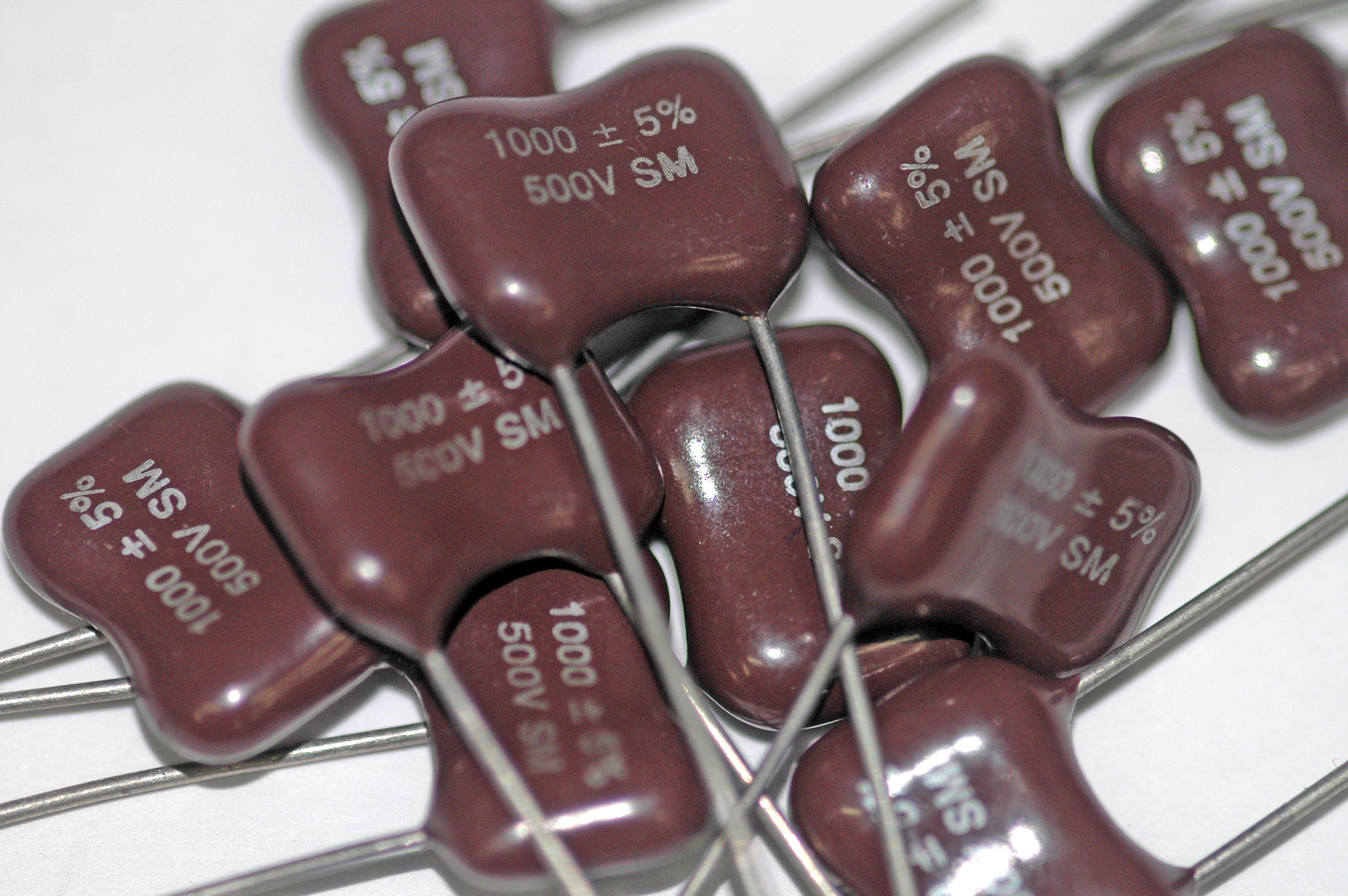 Figure 10 — Modern dipped silver-mica capacitors, marked alphanumerically rather than with dots. Source: Wikimedia Commons, user Mataresephotos, CC BY 3.0.
