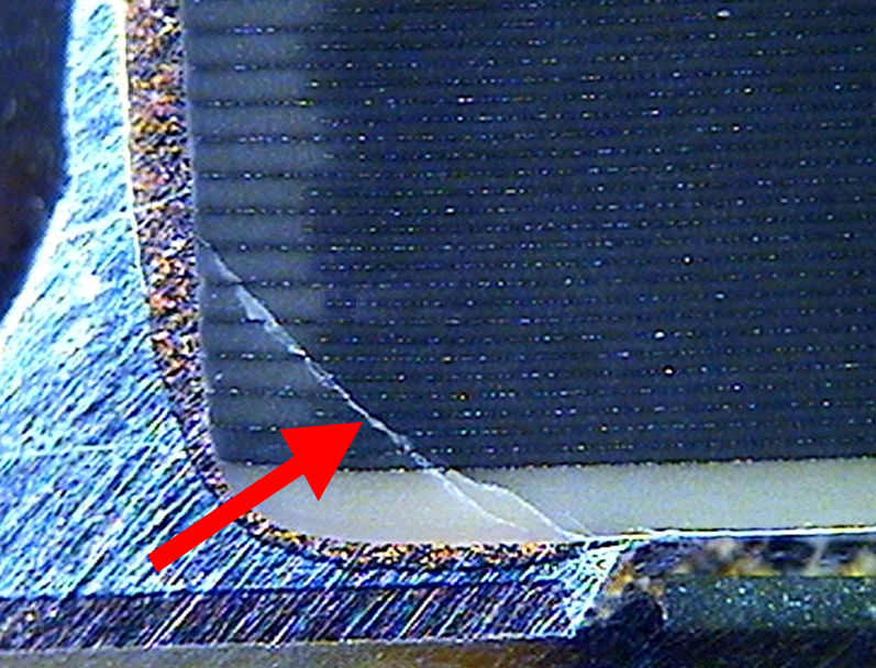 Figure 7 — Polished cross-section of an MLCC with a crack propagating through the ceramic body. Mechanical cracks like this — from board flex or thermal shock — are the dominant field-failure mode …