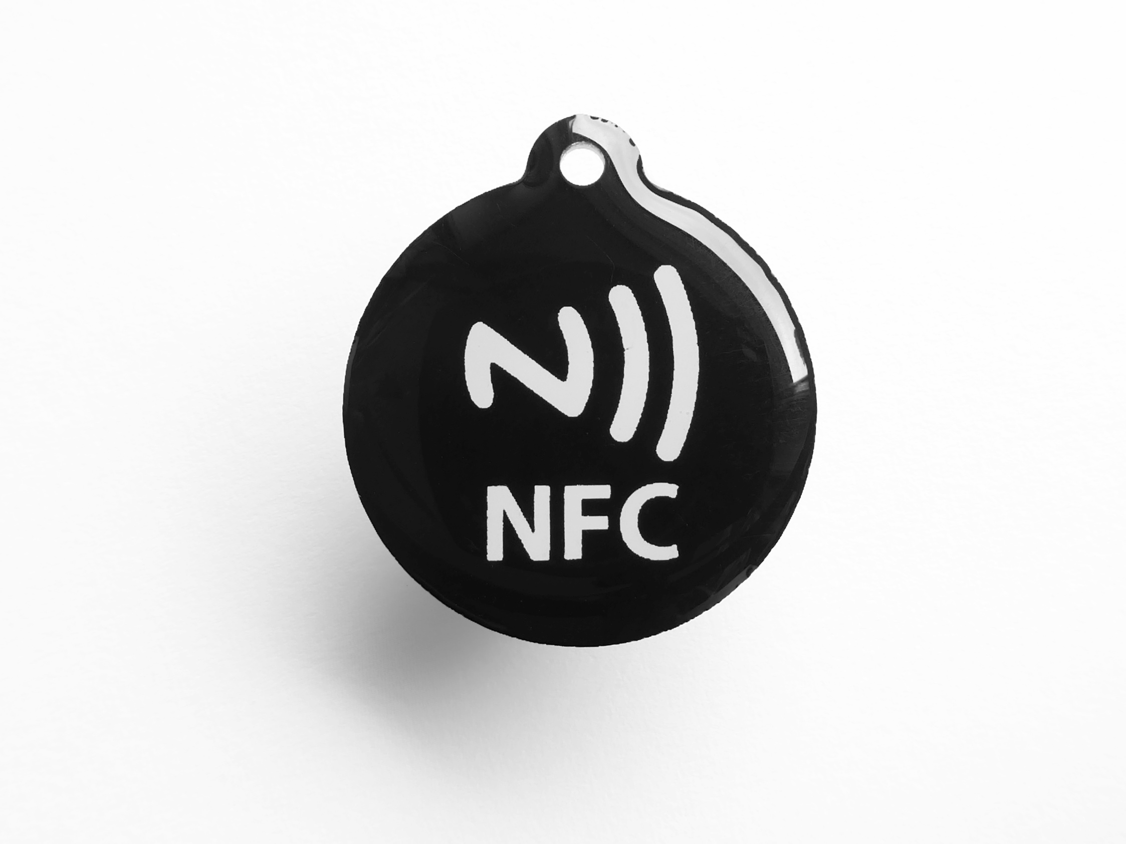 Figure 2 — An NFC tag chip in its glass-encapsulated package — the physical form factor that ships in NFC stickers, embedded in lamps and posters, and in the long tail of NFC-enabled consumer products. The ch…