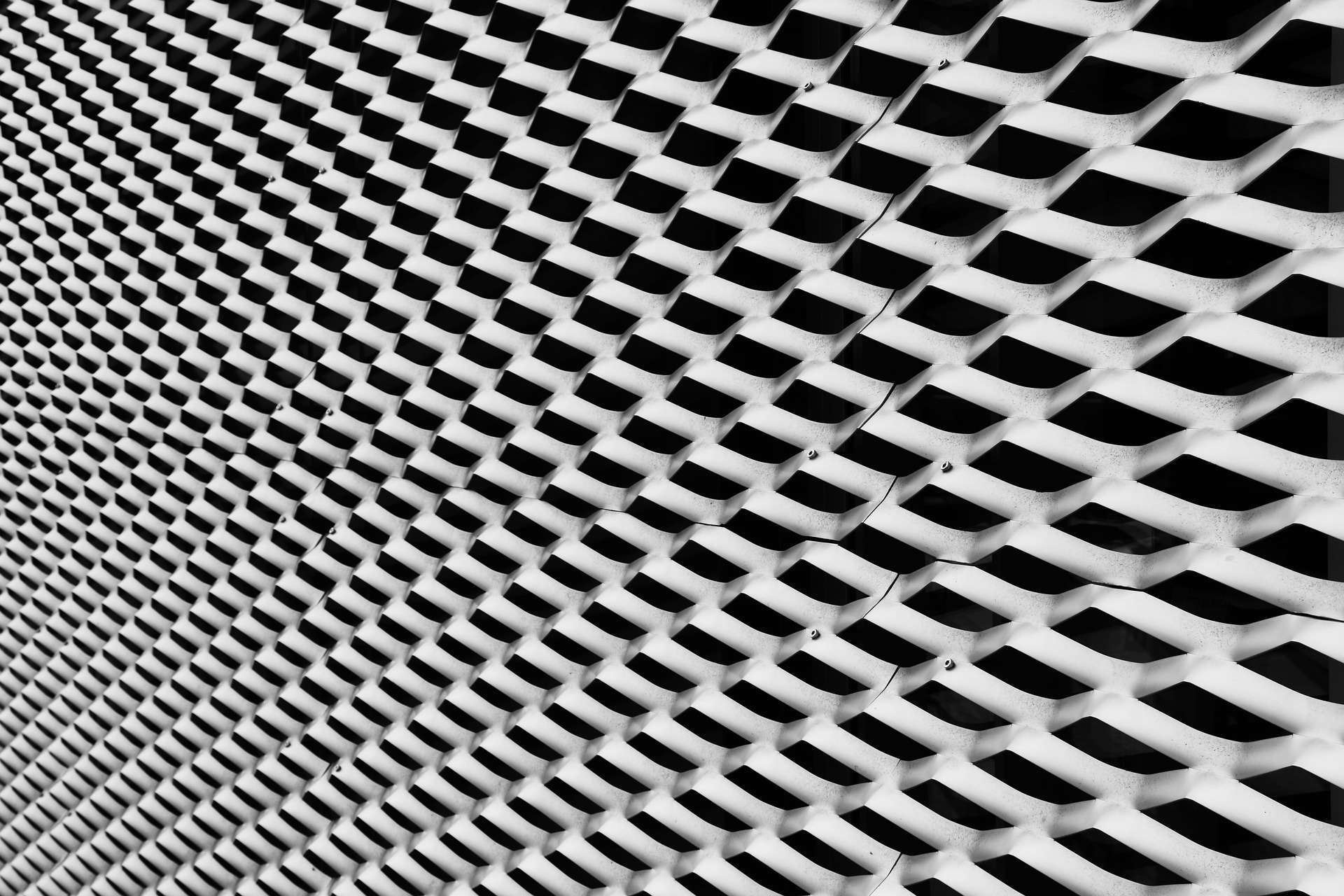 Figure 4 — Expanded metal mesh: sheet steel slit and stretched into a rigid diamond lattice. The Tech Spec's Wall B specifies 3/4-inch mesh in #9 (10-gauge) steel welded to the stud framing; becaus…
