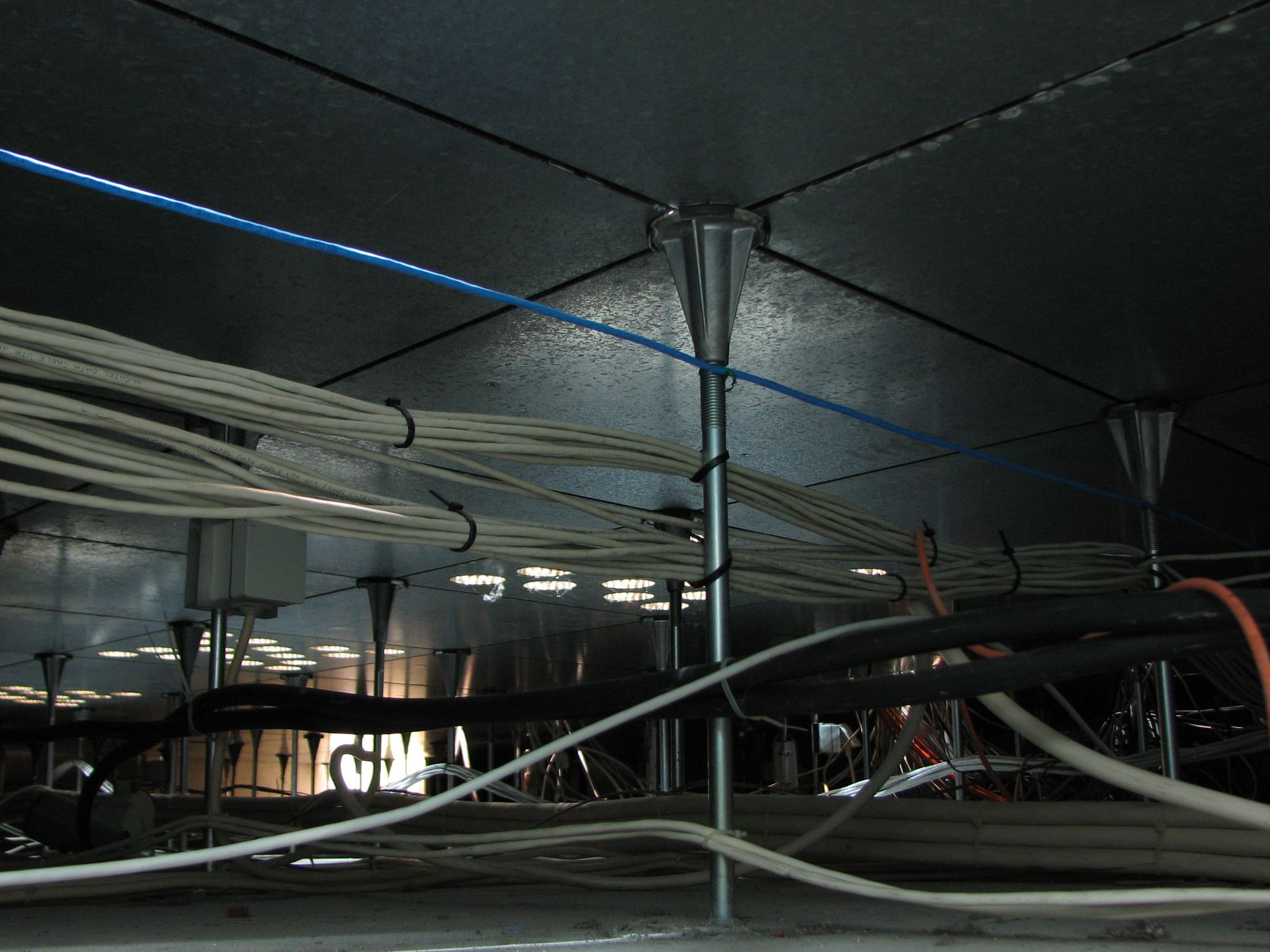 Figure 5 — The void beneath a raised access floor, packed with power and data cabling. Convenient for routing services, this under-floor plenum is inside the SCIF perimeter, never the perimeter its…