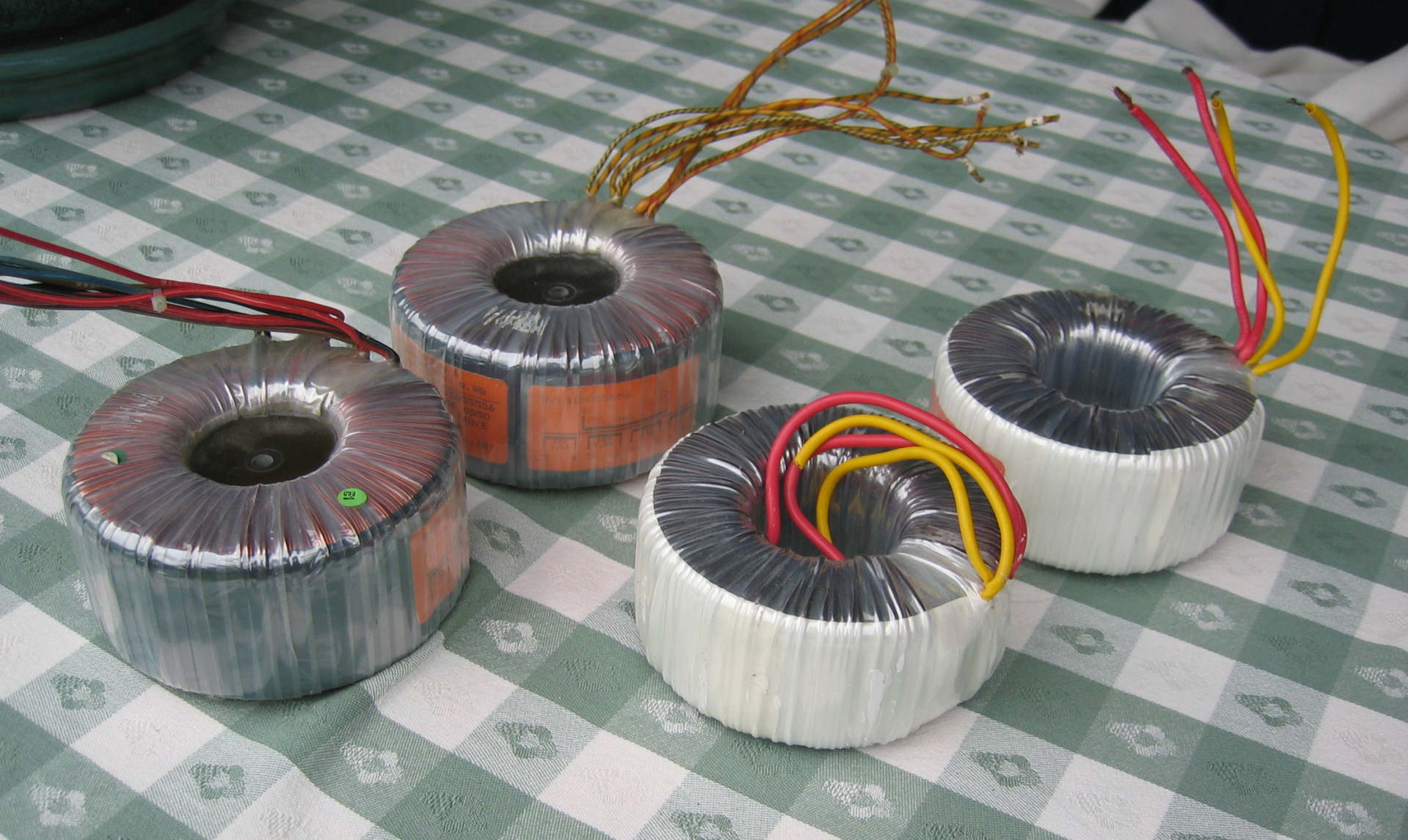 Figure 2 — A toroidal mains transformer: a continuous ribbon of grain-oriented silicon steel wound into a gapless ring, with the windings spread around it. The closed magnetic path gives low stray …